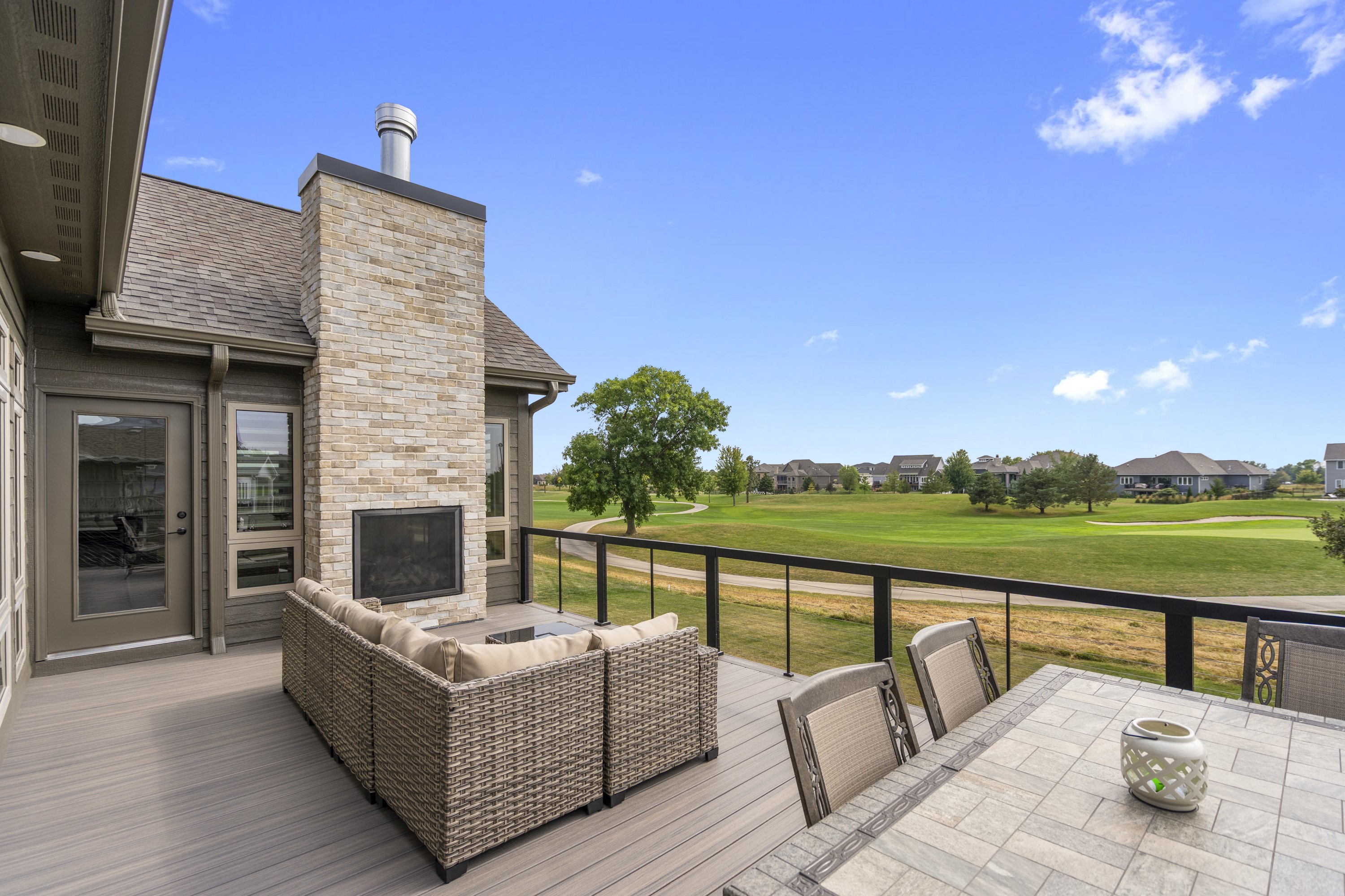 Deck with outdoor fireplace and golf course view