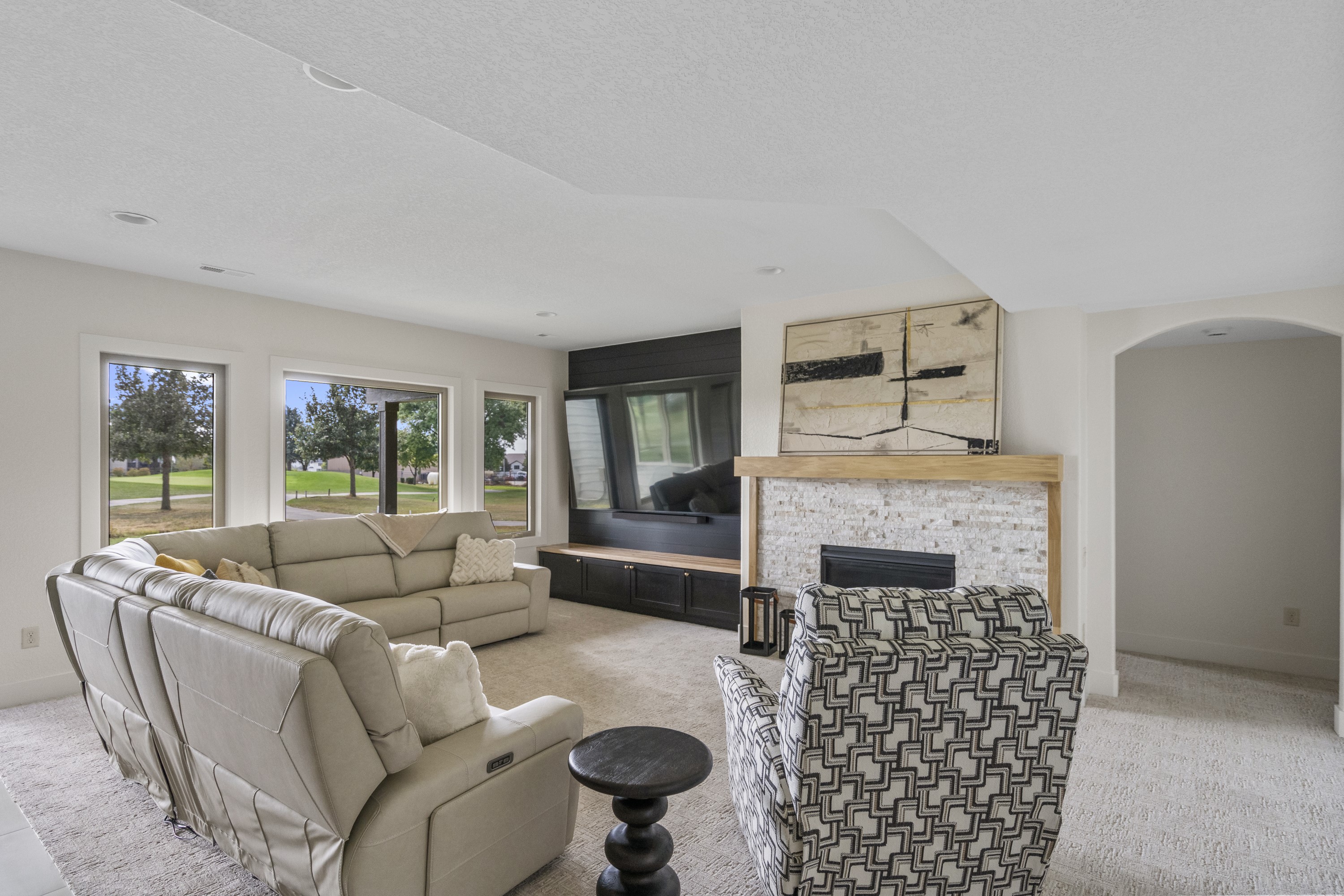 Open concept living room with stone fireplace, built-in entertainment center, and golf course views